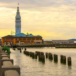Postcard-like image of the boardwalk/embarcadero leading to the Ferry Building in San Francisco. The sky is highlighted with gorgeous yellow pre-sunset cloud covering. door dlove (bron: shutterstock)