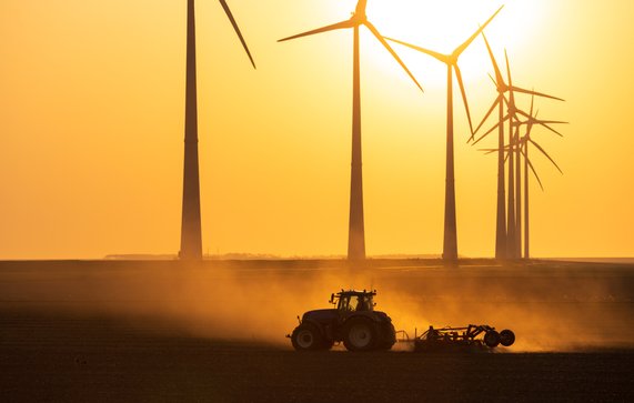 Tractor cultiveert landbouwgrond tijdens zonsondergang bij een rij windturbine. Groningen, Nederland. door Sander van der Werf (bron: Shutterstock)